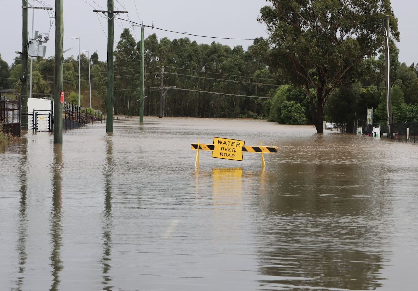 Flooded road with a sign saying “Water Over Road”.
